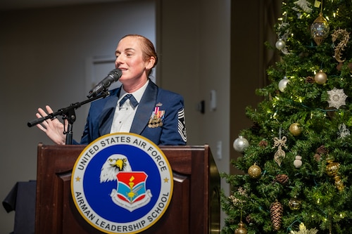 A woman, wearing formal Air Force dress military stand behind podium next to a holiday tree