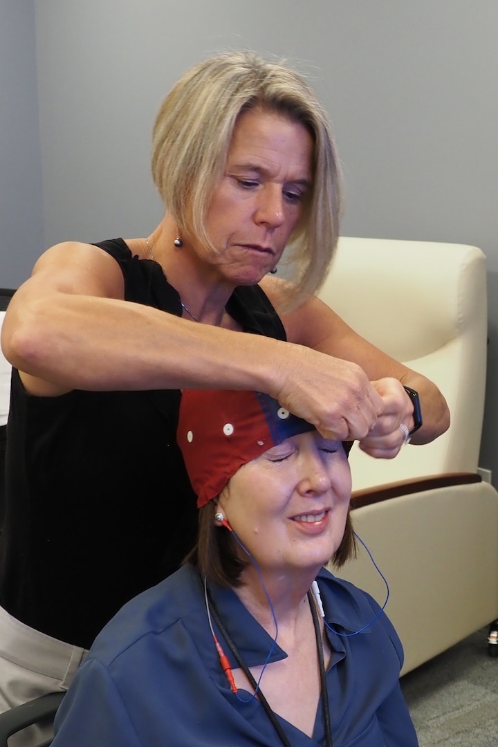 Kirsten Larson, a psychometrist with the Fort Carson Intrepid Spirit Center, helps place a neurofeedback Electro-Cap on Suzanne Martin, an ISC neuropsychologist, while testing out new equipment for use in treatment of traumatic brain injury and other diagnoses. Neurofeedback is an evidenced-based practice that allows clinicians to “map” brain activity levels and compare the results to what is considered normal brain activity.