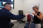 Public Health Service Lt. Austin D Hamilton, left, a licensed supervisory psychologist with the Fort Carson Intrepid Spirit Center, and Kirsten Larson, an ISC psychometrist, fine tune the connection on a neurofeedback Electro-Cap worn by Suzanne Martin, an ISC neuropsychologist, while testing out new equipment for use in treatment of traumatic brain injury and other diagnoses. Neurofeedback is an evidenced-based practice that allows clinicians to “map” brain activity levels and compare the results to what is considered normal brain activity.