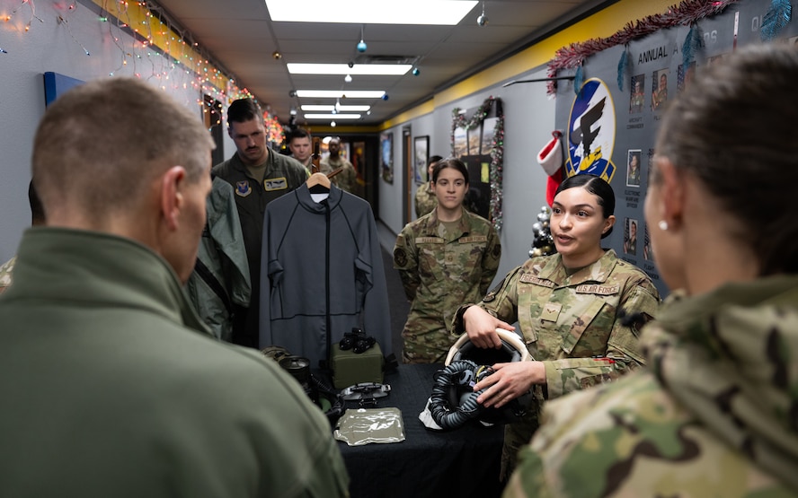 An Airman gives a presentation about pilots’ survival equipment to U.S. Navy Adm. Rich Correll (left).