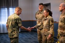 U.S. Navy Adm. Rich Correll (left) coins Airman 1st Class Zavia Eason through a handshake.
