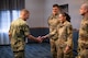 U.S. Navy Adm. Rich Correll (left) coins Airman 1st Class Zavia Eason through a handshake.