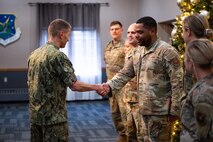 U.S. Navy Adm. Rich Correll (left) coins U.S. Air Force Tech. Sgt. Ra’Shad Patrick through a handshake.
