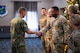 U.S. Navy Adm. Rich Correll (left) coins U.S. Air Force Tech. Sgt. Ra’Shad Patrick through a handshake.