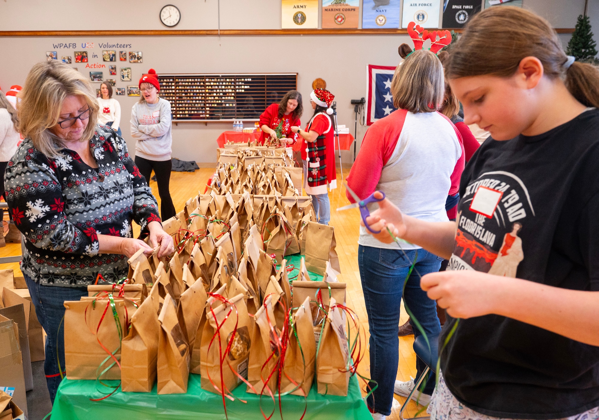 Women stand on either side of a long table working on bags of cookies.