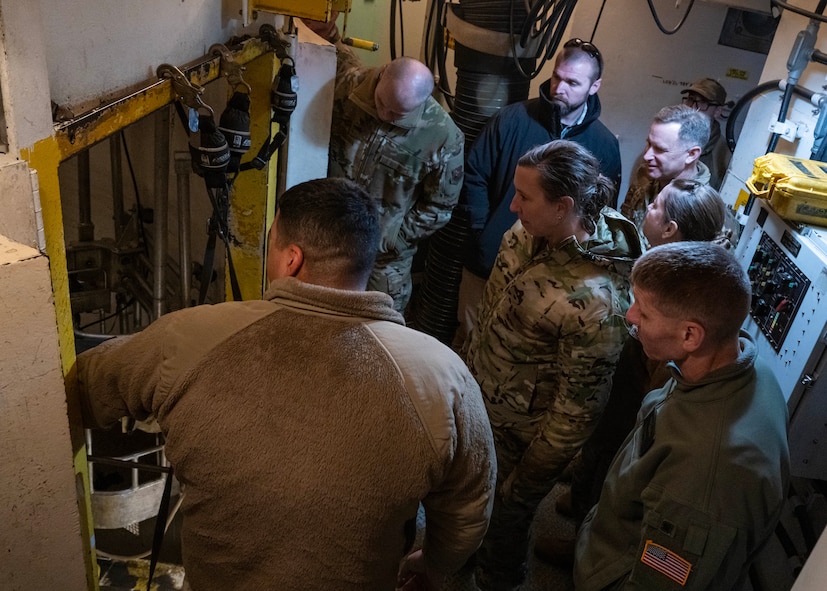 U.S. Navy Adm. Rich Correll receives a briefing from Airmen while inside of a training missile launch facility.