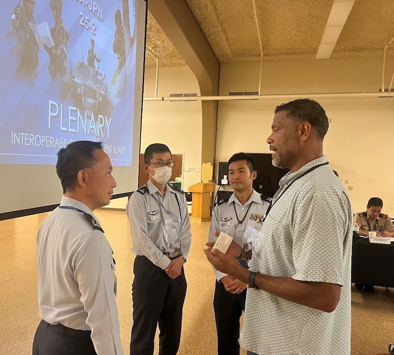 Dr. Andre Stridiron, Program Manager, Pacific Multi Domain Training and Experimentation Capability (r), converses with Japan Self Defense Force personnel (l to r) Col. Mishima Takeshi, Director, 2nd Force Structuring Division (Space & Cyber), ASO, Maj. Hayashi Tsuyoshi and Lt. Col. Ishida Takama at the U.S.-Japan Interoperability Management Board 25-2 closing plenary session at Marine Corps Base Hawaii, October 23, 2025.