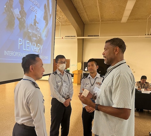 Dr. Andre Stridiron, Program Manager, Pacific Multi Domain Training and Experimentation Capability (r), converses with Japan Self Defense Force personnel (l to r) Col. Mishima Takeshi, Director, 2nd Force Structuring Division (Space & Cyber), ASO, Maj. Hayashi Tsuyoshi and Lt. Col. Ishida Takama at the U.S.-Japan Interoperability Management Board 25-2 closing plenary session at Marine Corps Base Hawaii, October 23, 2025.
