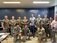 Participants in the III Marine Expeditionary Force Unmanned Systems Branch instructor course, and Pacific Multi Domain Training and Experimentation Capability Program Manager Dr. Andre Stridiron, display unmanned aircraft systems manufactured during the course at Camp Hansen, Okinawa, October 30, 2025.