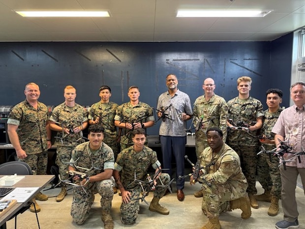 Participants in the III Marine Expeditionary Force Unmanned Systems Branch instructor course, and Pacific Multi Domain Training and Experimentation Capability Program Manager Dr. Andre Stridiron, display unmanned aircraft systems manufactured during the course at Camp Hansen, Okinawa, October 30, 2025.