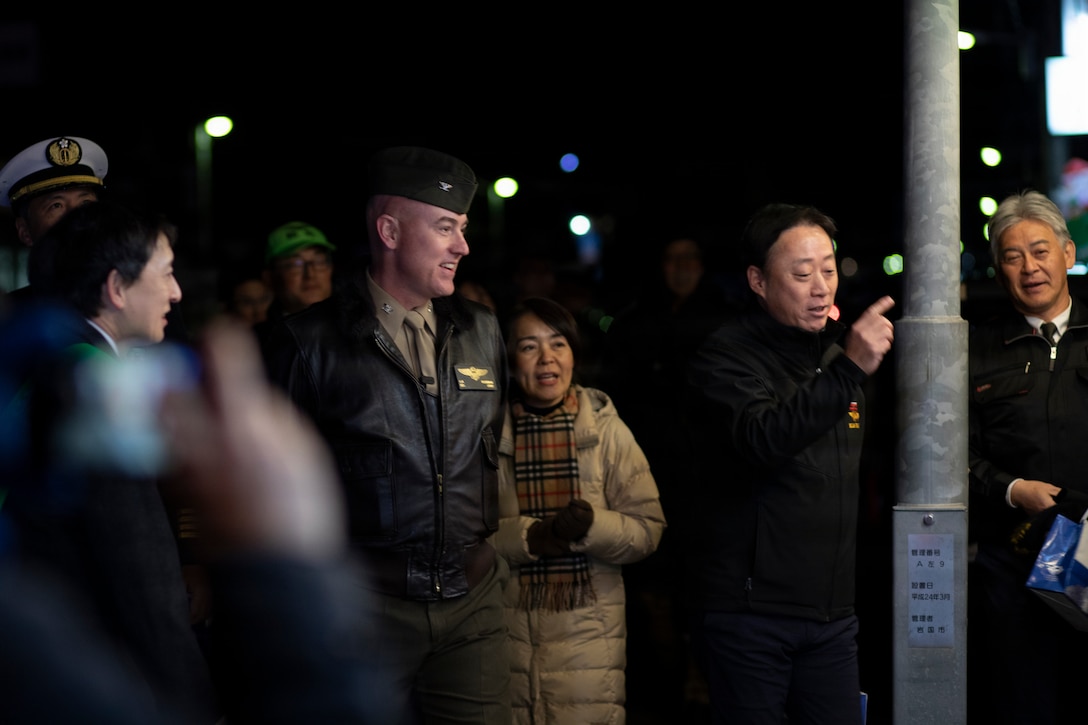 U.S. Marine Corps Col. Kenneth Rossman, center left, the Marine Corps Air Station Iwakuni commanding officer, and a native of Pittsburgh, Pennsylvania, and Mr. Fukuda Yoshihiko, center right, the Iwakuni city mayor, walk outside the MCAS Iwakuni main gate during a joint leadership walk at Iwakuni, Japan, Dec. 12, 2025. Leadership from MCAS Iwakuni, Iwakuni City, and Fleet Air Wing 31, toured Iwakuni city, spoke to citizens, news organizations and local business owners, strengthening relationships between the local and on-base communities. (U.S. Marine Corps photo by Lance Cpl. Tyler Bassett)