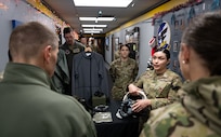 An Airman gives a presentation about pilots’ survival equipment to U.S. Navy Adm. Rich Correll (left).