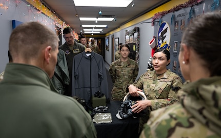 An Airman gives a presentation about pilots’ survival equipment to U.S. Navy Adm. Rich Correll (left).