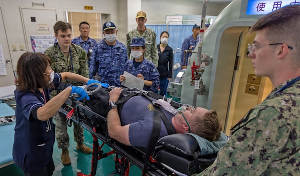 TAURA, Japan (Nov. 18, 2025) — Medical personnel from U.S. Naval Hospital Yokosuka and the Japan Maritime Self-Defense Force Undersea Medical Center conduct a rapid evaluation of a simulated diving casualty during a bilateral emergency medical drill. The exercise rehearsed coordinated response, transport, and evaluation procedures for a simulated diving-related embolism. (U.S. Navy photo by Daniel Taylor/USNMRTC Yokosuka Public Affairs)