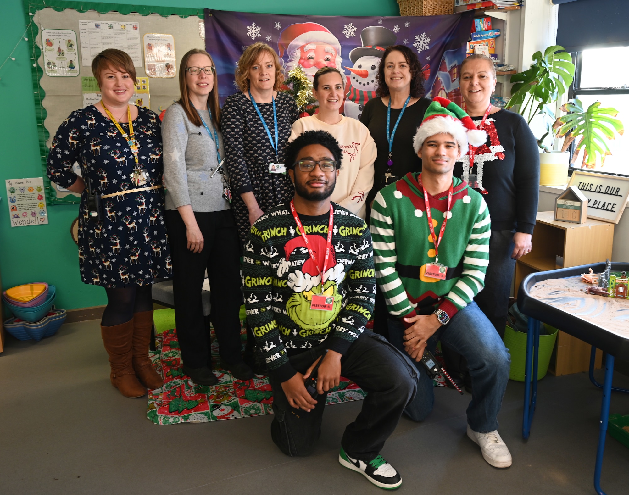 Staff from Great Heath Academy pose for a photo with U.S. Air Force Senior Airman Savion Watson, front right, 100th Communications Squadron agile combat employment technician; Airman 1st Class Jeffrey Favor, center, 100th CS radiofrequency transmissions technician, and Natalie Murphy, far right, RAF Mildenhall community relations advisor, during the Radio Santa event at the primary school in Mildenhall, Suffolk, Dec. 10, 2025. RAF Mildenhall regularly volunteer within the local community to strengthen partnerships. (U.S. Air Force photo by Karen Abeyasekere)