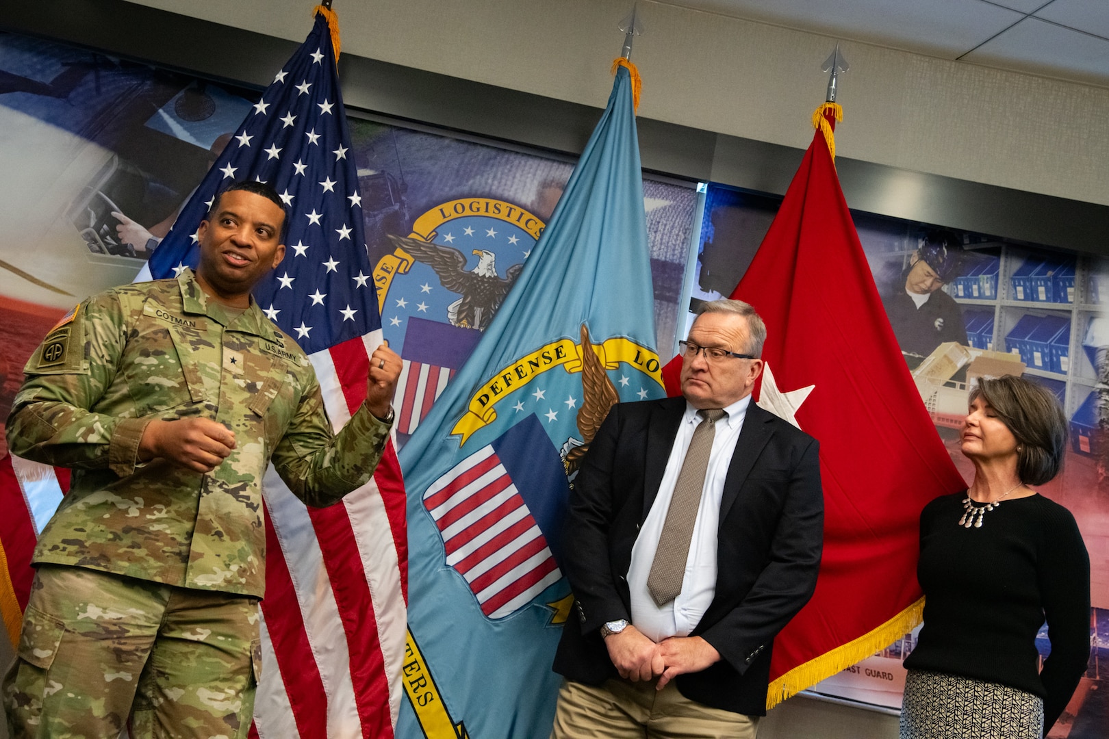 Two people at an award ceremony standing in front of flags.