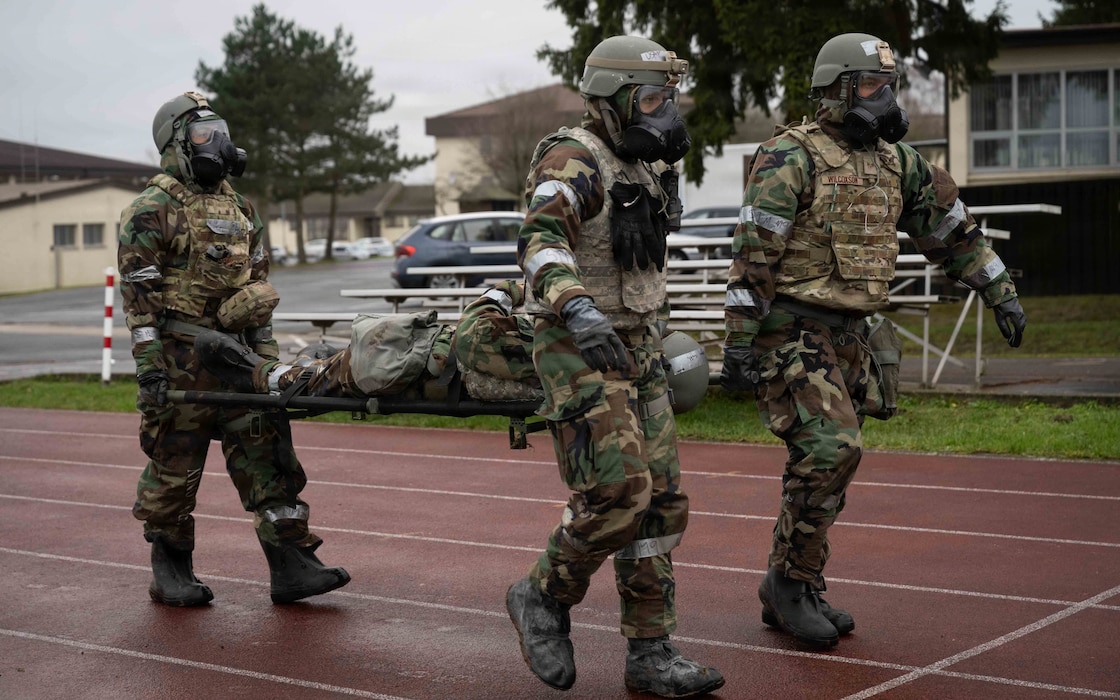 Airmen assigned to the 52nd Civil Engineer Squadron transport a notional casualty during a combat beddown readiness exercise at Spangdahlem Air Base, Germany, Dec. 5th, 2025. The scenario-focused training emphasized Tactical Combat Casualty Care skills in a chemically hazardous area. (U.S. Air Force photo by Senior Airman Darius Frazier)