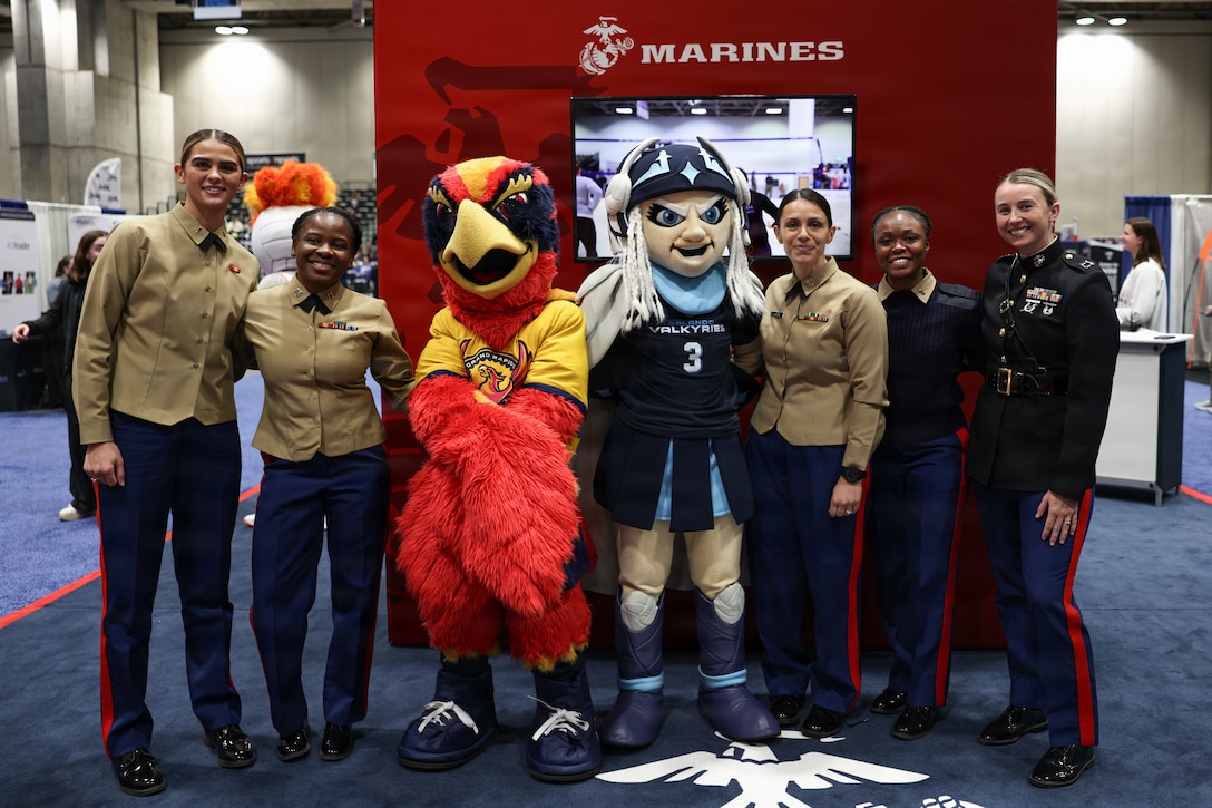 U.S. Marines pose for a photo at a U.S. Marine Corps booth during the American Volleyball Coaches Association Volleyball Marketplace in Kansas City, Missouri, Dec. 18, 2025. The engagement supports Marine Corps recruiting commands efforts to build relationships and create advocacy with coaches and influencers throughout the country. (U.S. Marine Corps photo by Cpl. Hana Lathrop)