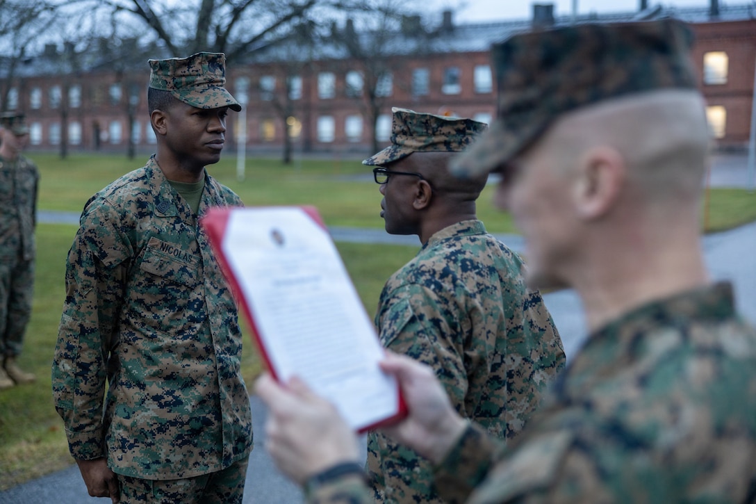 U.S. Marine Corps 1st Sgt. Herbert Nicolas, left, a senior enlisted advisor with Combat Logistics Battalion 6, Combat Logistics Regiment 2, 2nd Marine Logistics Group, and Lt. Col. Terry Whitaker, center, commanding officer of CLB 6, CLR 2, 2nd MLG, stand at attention, while Sgt. Maj. Tristan Curren, sergeant major of CLB 6, CLR 2, 2nd MLG, reads a promotion warrant, during a promotion ceremony as part of Exercise Freezing Winds 2025 in Dragsvik, Finland, Dec. 11, 2025. Freezing Winds is conducted to increase interoperability between Marines, Finland, and NATO Allies by executing combined amphibious operations in and around the Baltic Sea littorals, and is part of a regularly occurring series of exercises in northern Europe that demonstrates the capability to deploy and train Marines and Sailors in support of the NATO Alliance. Nicholas is a native of New York. Whitaker is native of Georgia. Curren is a native of Washington. (U.S. Marine Corps photo by Cpl. Apollo Wilson)
