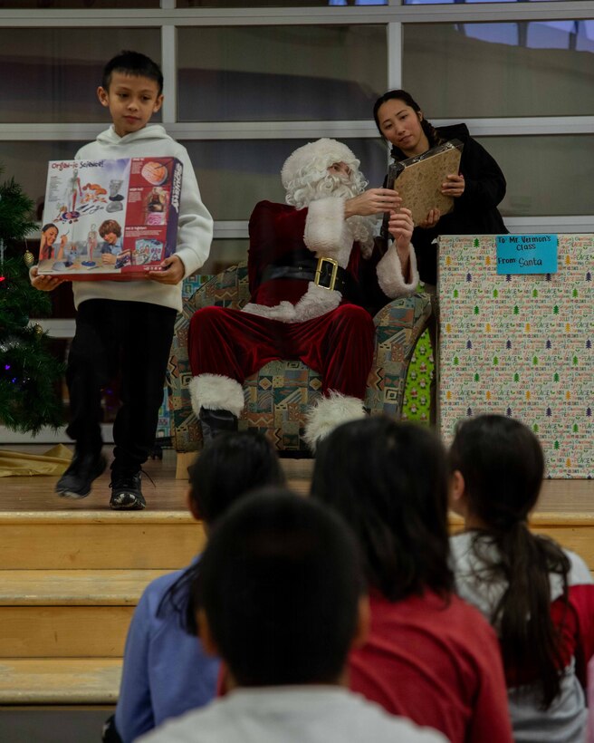 U.S. Marine Corps Capt. Daniel Kelly dressed as Santa Claus greets a child attending June Nelson Elementary School in Kotzebue, Alaska, Dec. 8, 2025. Kelly, a military police officer and Inspector Instructor with 4th Law Enforcement Battalion, Force Headquarters Group delivered toys to the school with the assistance of Marines from Detachment Delta Company and U.S. Airmen from various units during this year’s Toys for Tots operation. The Toys for Tots mission exemplifies the Marine Corps spirit in the Last Frontier, strengthening community ties while sharpening the Marines' readiness for Arctic operations. (U.S. Marine Corps photo by Cpl. Orion Stpierre)