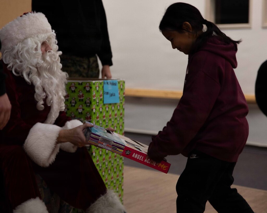 U.S. Marine Corps Capt. Daniel Kelly dressed as Santa Claus, greets a child attending June Nelson Elementary School in Kotzebue, Alaska, Dec. 8, 2025. Kelly, a military police officer and Inspector Instructor with 4th Law Enforcement Battalion, Force Headquarters Group delivered toys to the school with the assistance of Marines from Detachment Delta Company and U.S. Airmen from various units during this year’s Toys for Tots operation. The Toys for Tots mission exemplifies the Marine Corps spirit in the Last Frontier, strengthening community ties while sharpening the Marines' readiness for Arctic operations. (U.S. Marine Corps photo by Cpl. Orion Stpierre)