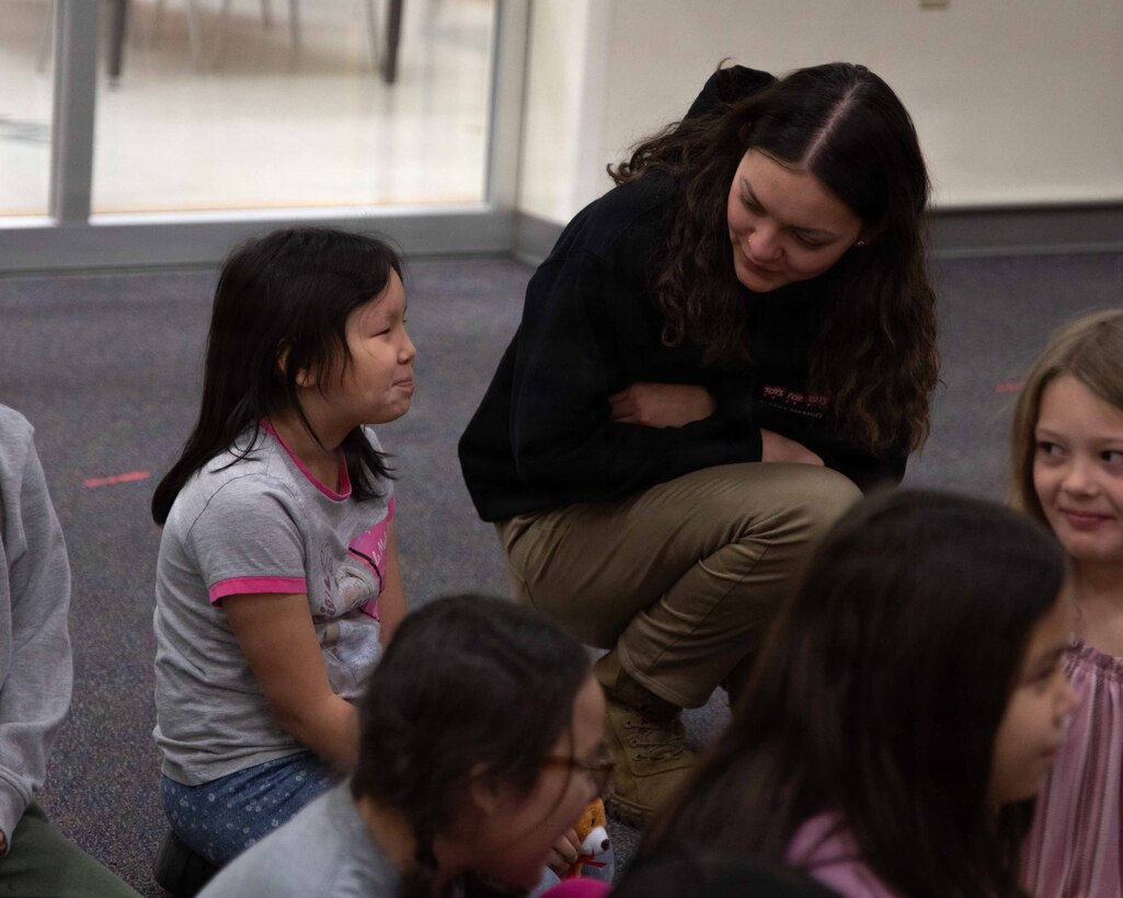 U.S Airforce Senior Airman Amy Ayala greets a child attending June Nelson Elementary School in Kotzebue, Alaska, Dec. 8, 2025. Ayala is a security forces member with 673rd Security Forces Squadron. The Airmen and Marines delivered toys to the school with the assistance of Marines from Detachment Delta Company and U.S. Airmen from various units during this year’s Toys for Tots operation. The Toys for Tots mission exemplifies the Marine Corps spirit in the Last Frontier, strengthening community ties while sharpening the Marines' readiness for Arctic operations. (U.S. Marine Corps photo by Cpl. Orion Stpierre)