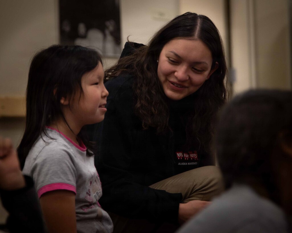 U.S. Airforce Senior Airman Amy Ayala greets a child attending June Nelson Elementary School in Kotzebue, Alaska, Dec. 8, 2025. Ayala is a security forces member with 673rd Security Forces Squadron. The Airmen and Marines delivered toys to the school with the assistance of Marines from Detachment Delta Company and U.S. Airmen from various units during this year’s Toys for Tots operation. The Toys for Tots mission exemplifies the Marine Corps spirit in the Last Frontier, strengthening community ties while sharpening the Marines' readiness for Arctic operations. (U.S. Marine Corps photo by Cpl. Orion Stpierre)