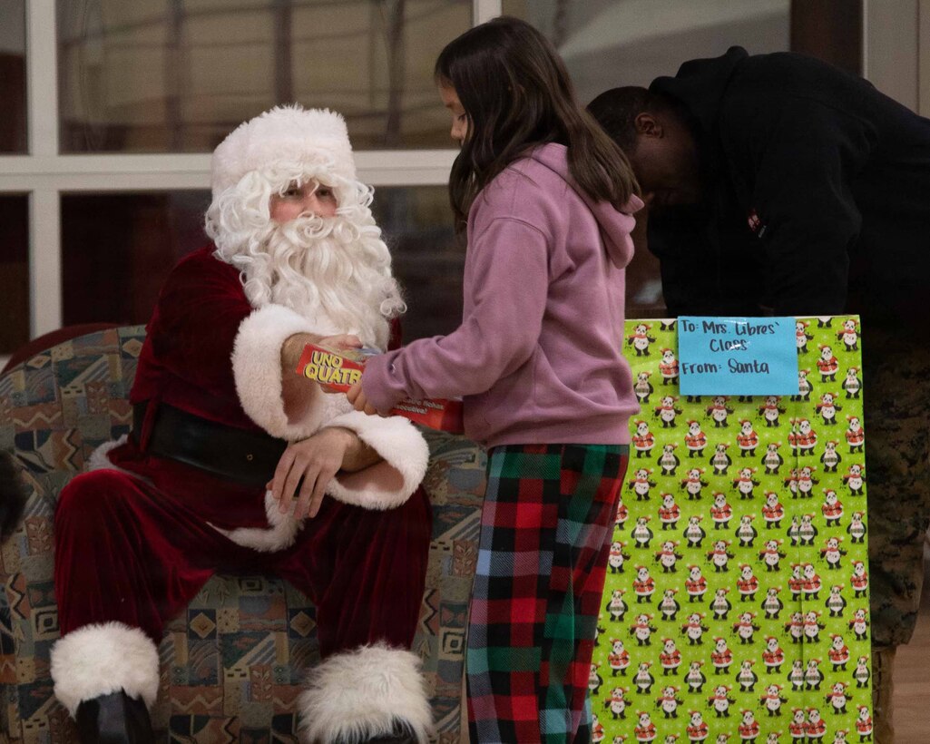 U.S. Marine Corps Capt. Daniel Kelly dressed as Santa Claus, greets a child attending June Nelson Elementary School in Kotzebue, Alaska Dec. 8, 2025. Kelly, a military police officer and Inspector Instructor with 4th Law Enforcement Battalion, Force Headquarters Group delivered toys to the school with the assistance of Marines from Detachment Delta Company and U.S. Airmen from various units during this year’s Toys for Tots operation. The Toys for Tots mission exemplifies the Marine Corps spirit in the Last Frontier, strengthening community ties while sharpening the Marines' readiness for Arctic operations. (U.S. Marine Corps photo by Cpl. Orion Stpierre)