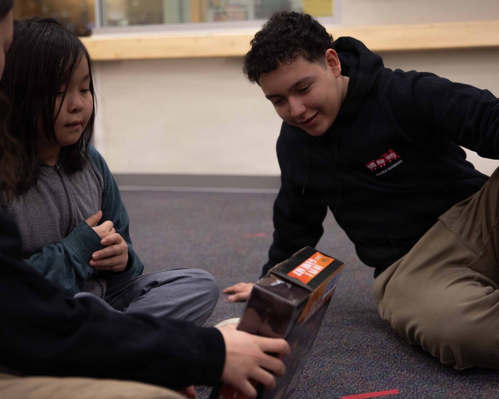 U.S. Air Force Airman Aidan Facio greets a child attending June Nelson Elementary School in Kotzebue, Alaska, Dec. 8, 2025. Facio is a security forces member with the 673rd Security Forces Squadron and an Arizona native. The Marines with 4th Law Enforcement Battalion, Force Headquarters Group delivered toys to the school with the assistance of U.S. airmen from various units during this year’s Toys for Tots operation. The Toys for Tots mission exemplifies the Marine Corps spirit in the Last Frontier, strengthening community ties while sharpening the Marines' readiness for Arctic operations.