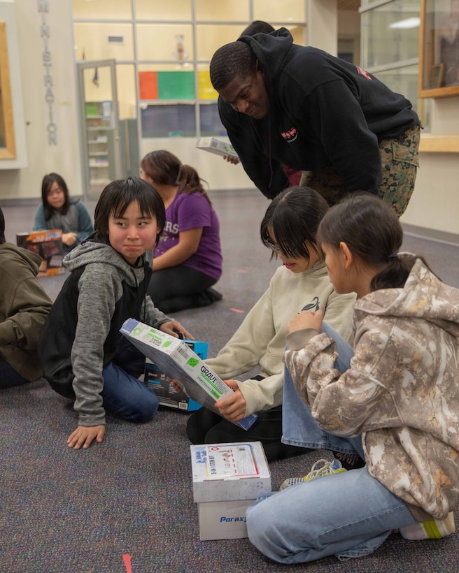 U.S. Marine Corps Staff Sgt. Tyreese Green greets a child attending June Nelson Elementary School in Kotzebue, Alaska, Dec. 8, 2025. Green is a supply chain and materiel specialist with Detachment D Company, 4th Law Enforcement Battalion, Force Headquarters Group. The Marines with 4th LEB, and U.S. Airmen from various units participated during this year’s Toys for Tots operation. The Toys for Tots mission exemplifies the Marine Corps spirit in the Last Frontier, strengthening community ties while sharpening the Marines' readiness for Arctic operations. (U.S. Marine Corps photo by Cpl. Orion Stpierre)