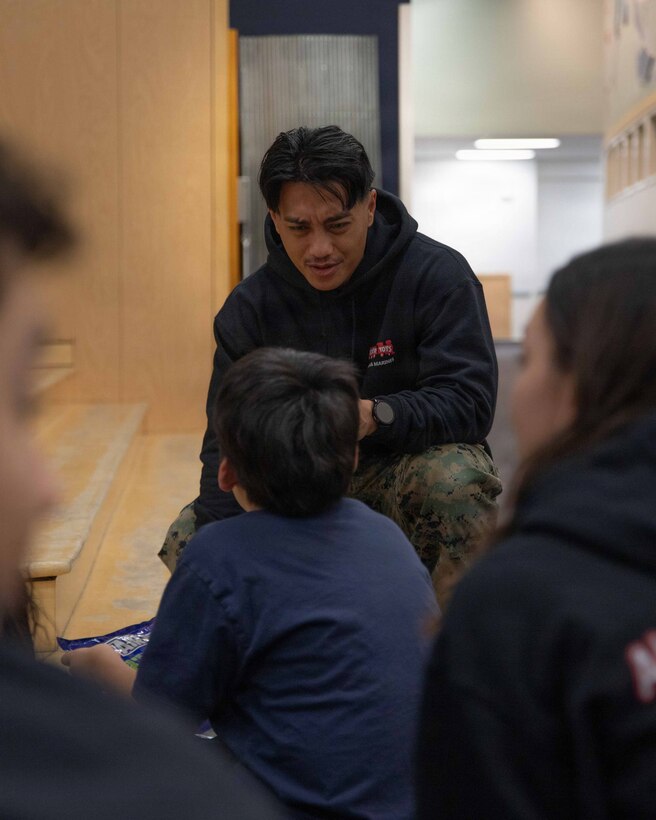 U.S. Marine Corps Gunnery Sgt. Niko Q. Azucenas greets a small class of children attending June Nelson Elementary School in Kotzebue, Alaska, Dec. 8, 2025. Azucenas is a military police officer with Detachment D Company, 4th Law Enforcement Battalion, Force Headquarters Group and is a native of Texas. Marines with 4th LEB delivered toys to the school with the assistance of U.S. Airmen from various units during this year’s Toys for Tots operation. The Toys for Tots mission exemplifies the Marine Corps spirit in the Last Frontier, strengthening community ties while sharpening the Marines' readiness for Arctic operations. (U.S. Marine Corps photo by Cpl. Orion Stpierre)