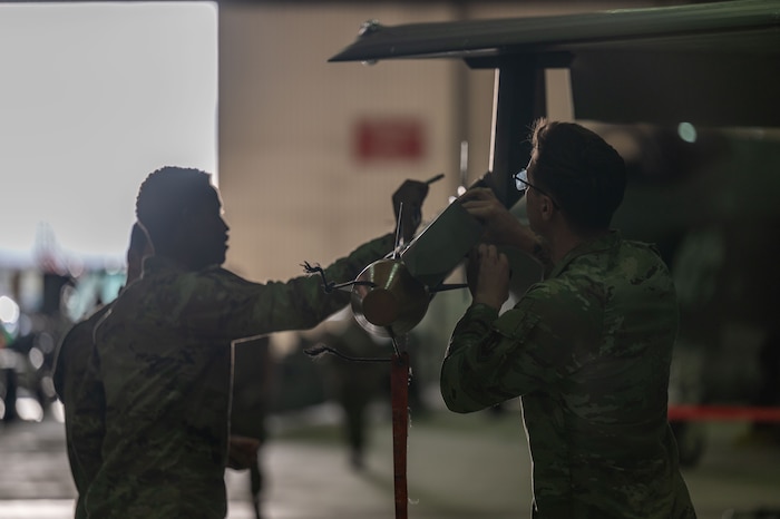 Military members load munitions on a plane.