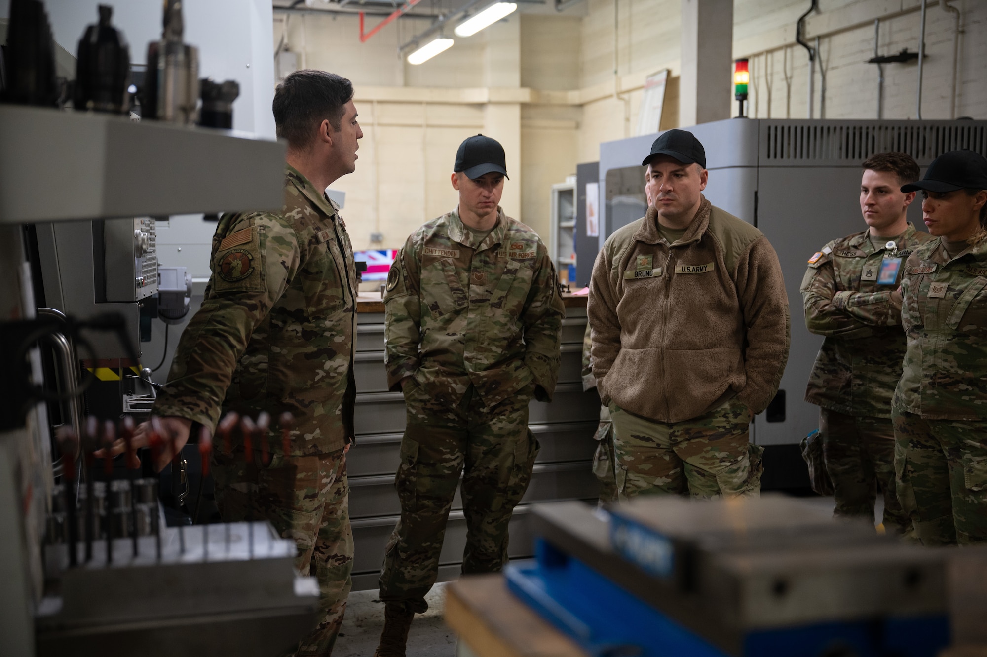 Military members stand around machinery.