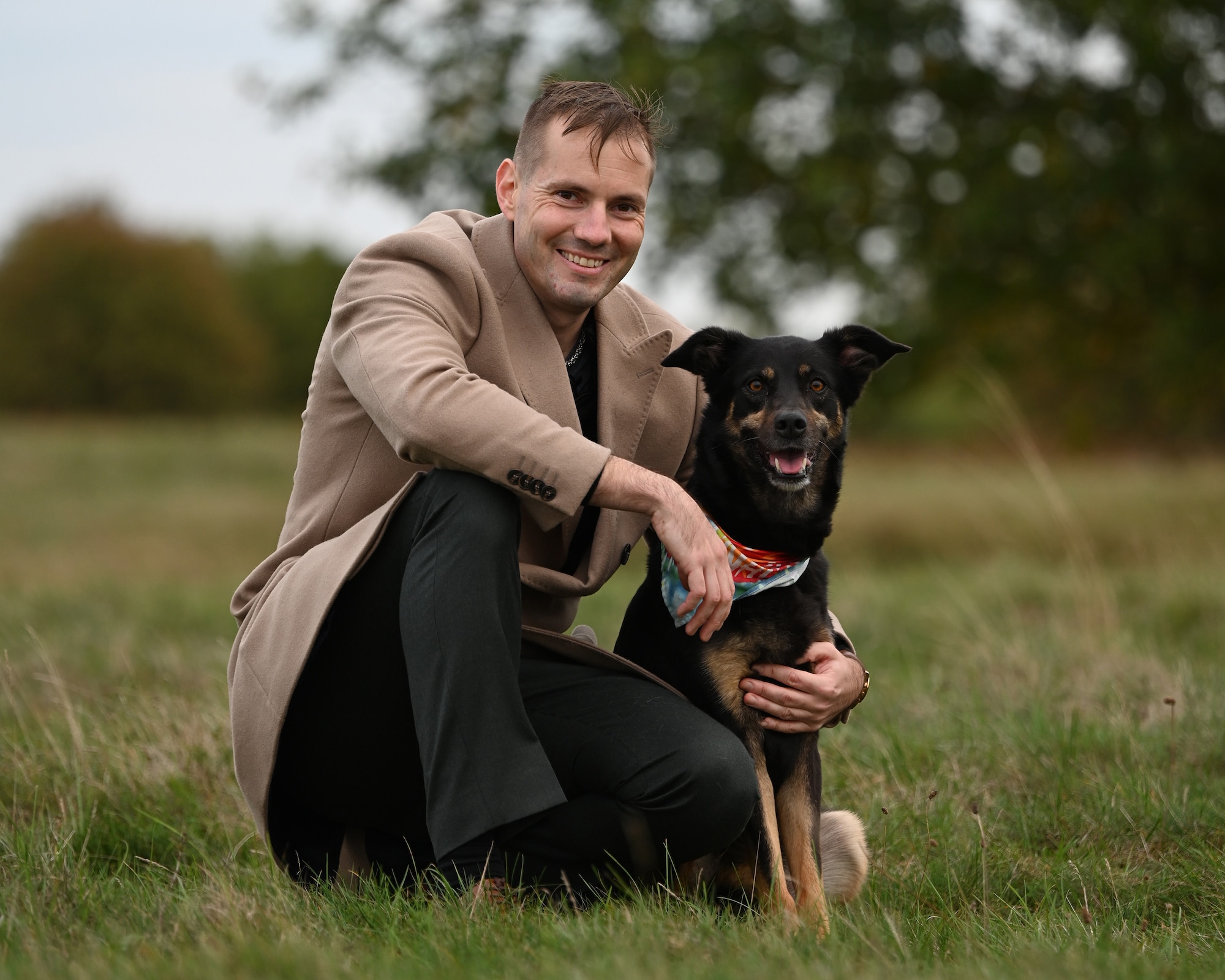 U.S. Air Force Master Sgt. Timka Peltonen, 488th Intelligence Squadron, takes time out for a photo with Tyttö, his Australian Shepherd/lab-cross, in Lakenheath, England, Oct. 9, 2025. After a lot of hard work and self-referring with the Alcohol and Drug Abuse Prevention and Treatment program three times between 2016 to 2019, Peltonen now has a bright future and a positive attitude. Tyttö has been with him throughout his struggles over the years and is the rescue dog who rescued him in return. Peltonen was recently selected for the Air Force’s Warrant Officer Training School. (U.S. Air Force photo by Karen Abeyasekere)