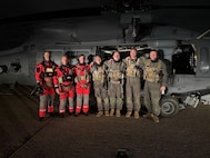 Three Pararescue Airmen from the 131st Rescue Squadron, 129th Rescue Wing, California Air National Guard, at left in orange, join for a group photo at Moffett Air National Guard Base in Mountain View with HH-60W Jolly Green II helicopter aircrew members from the 129th Rescue Squadron, early in the morning of Dec. 17 after rescuing a woman with a medical emergency from the Ruby Princess cruise ship 130 nautical miles southwest of San Francisco.