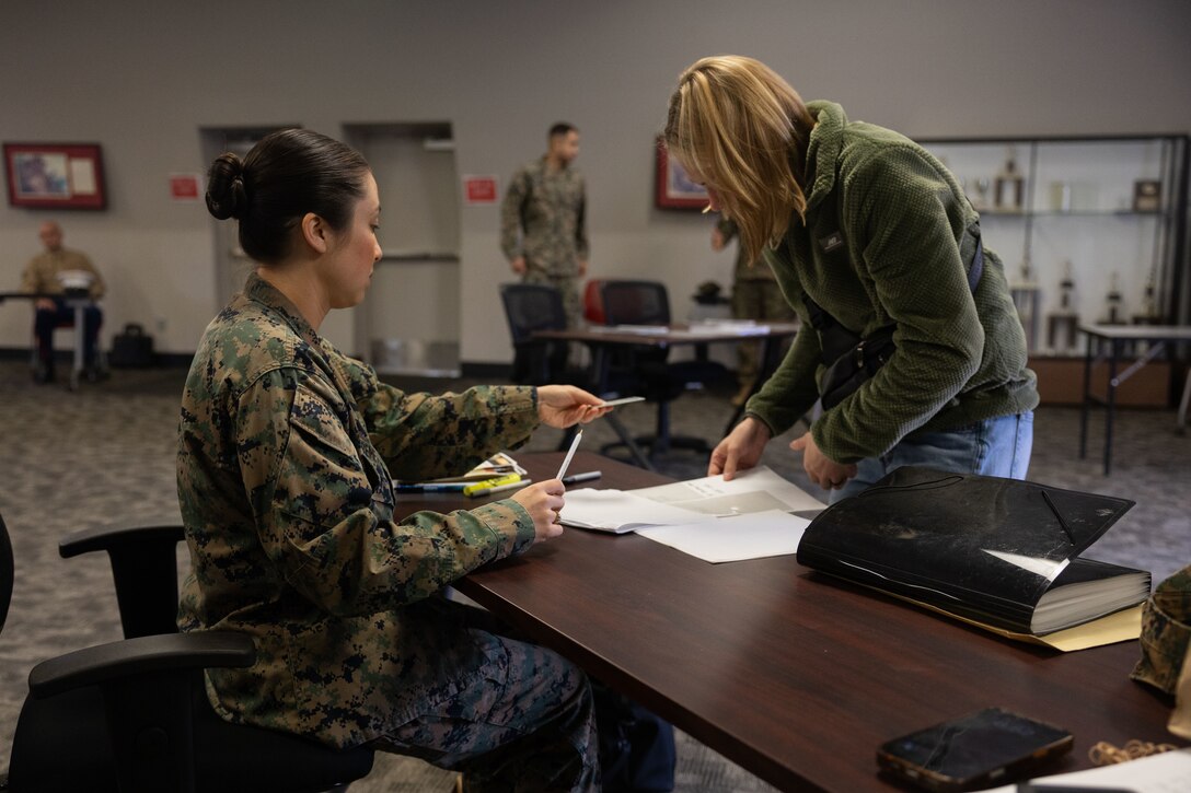 Maj. Siwen Cremean assists Sgt. Alexis Zavatkay during the check-in process of an Individual Ready Reserve (IRR) muster at Camp Pendleton, California, Dec. 14, 2025. Zavatkay is a Marine in the IRR and Cremean is a readiness support program operations officer with Marine Corps Individual Reserve Support Activity (MCIRSA), Force Headquarters Group, Marine Forces Reserve. During these muster events, MCIRSA conducts an administrative screening of IRR Marines to ensure their readiness to augment and reinforce the active component. (U.S. Marine Corps photo by Sgt. Emily De La Torre)