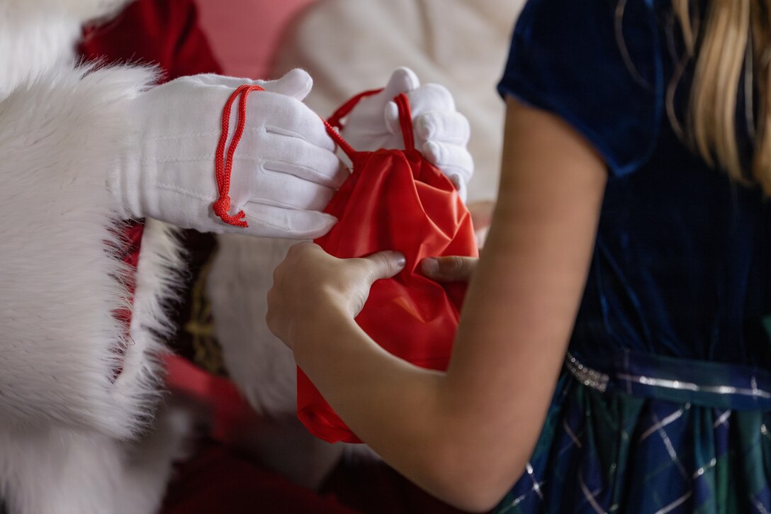 Santa Claus gifts a child with a goodie bag at a Toys for Tots charity event on Marine Corps Base Quantico, Virginia, Dec. 8, 2025. Since 1947, the Marine Corps Reserve has spearheaded the Toys for Tots program nationwide to collect toys for less fortunate children during the holiday season. Presently, the program distributes 7 to 18 million toys to children annually. (U.S. Marine Corps photo by Lance Cpl. Van Hoang)