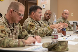 Men in military uniforms gather around a table.