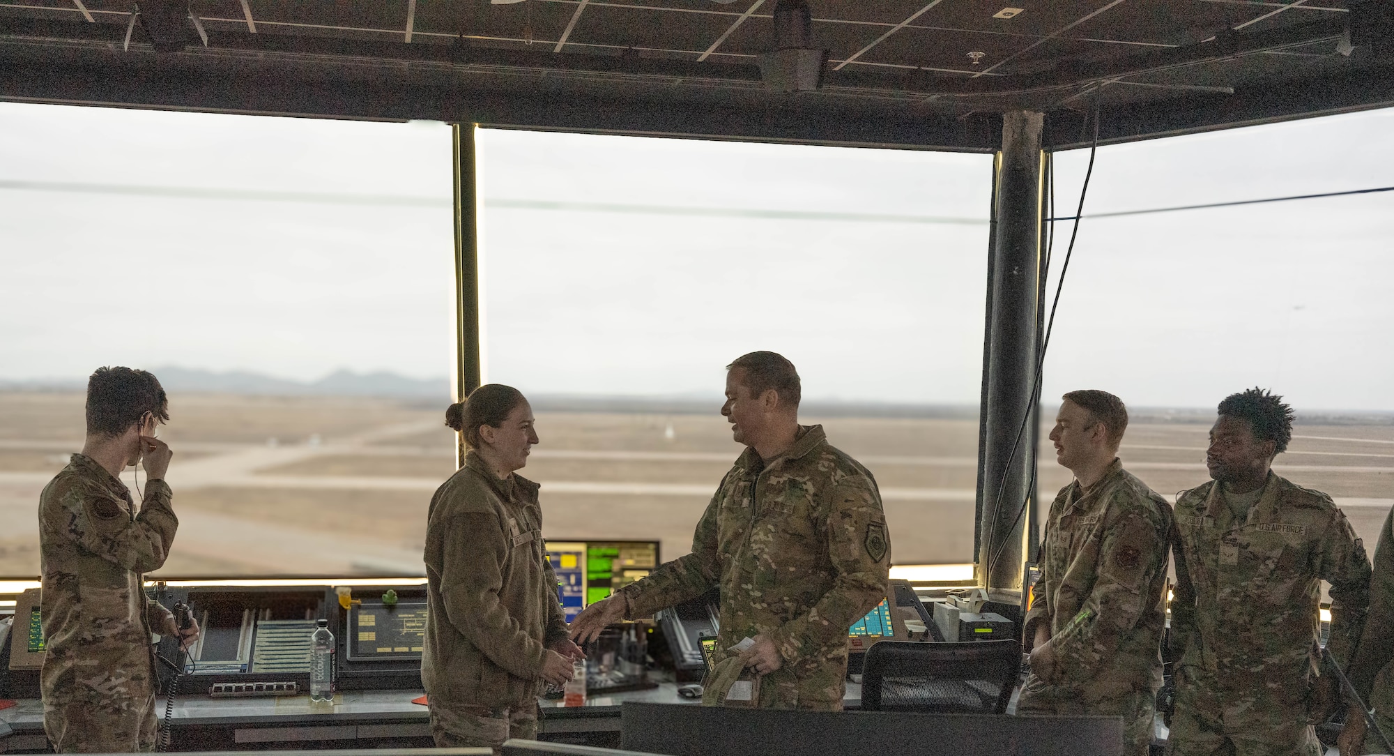 U.S. Air Force Col. Richard Kind, 97th Air Mobility Wing commander, coins U.S. Air Force Senior Airman Sarah Luce, 97th Operations Support Squadron air traffic control trainer, at Altus Air Force Base, Oklahoma, Dec. 15, 2025. Luce was recognized as the 2025 fiscal year Air Education and Training Command Airfield Operations Trainer of the Year, rewarding her exceptional performance and commitment to her duties. (U.S. Air Force photo by Airman 1st Class Emma Wright) 
This photo was altered for security purposes by blurring out flight monitors.