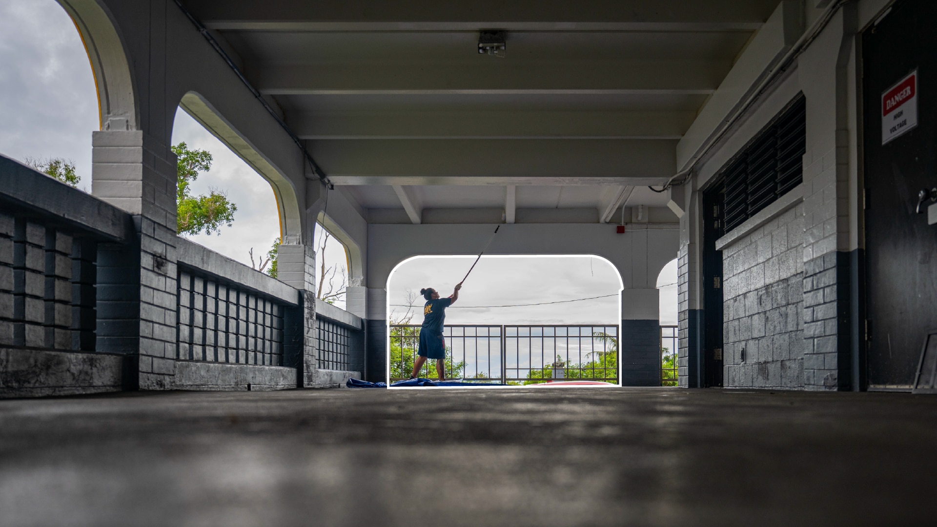 A sailor uses a cleaning tool to clean the exterior building arch of a middle school.