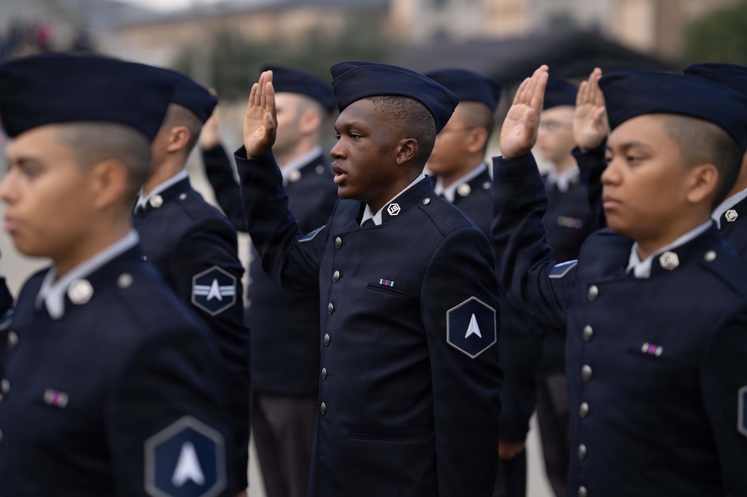 Guardians in ceremonial dress raise their right hands while reciting an oath on a gloomy day.