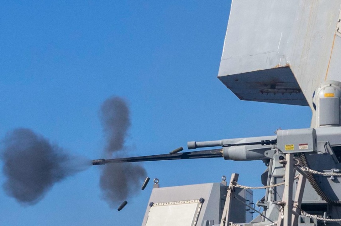 Ammo falls as a ship fires a weapon, creating black clouds of smoke in a blue sky.