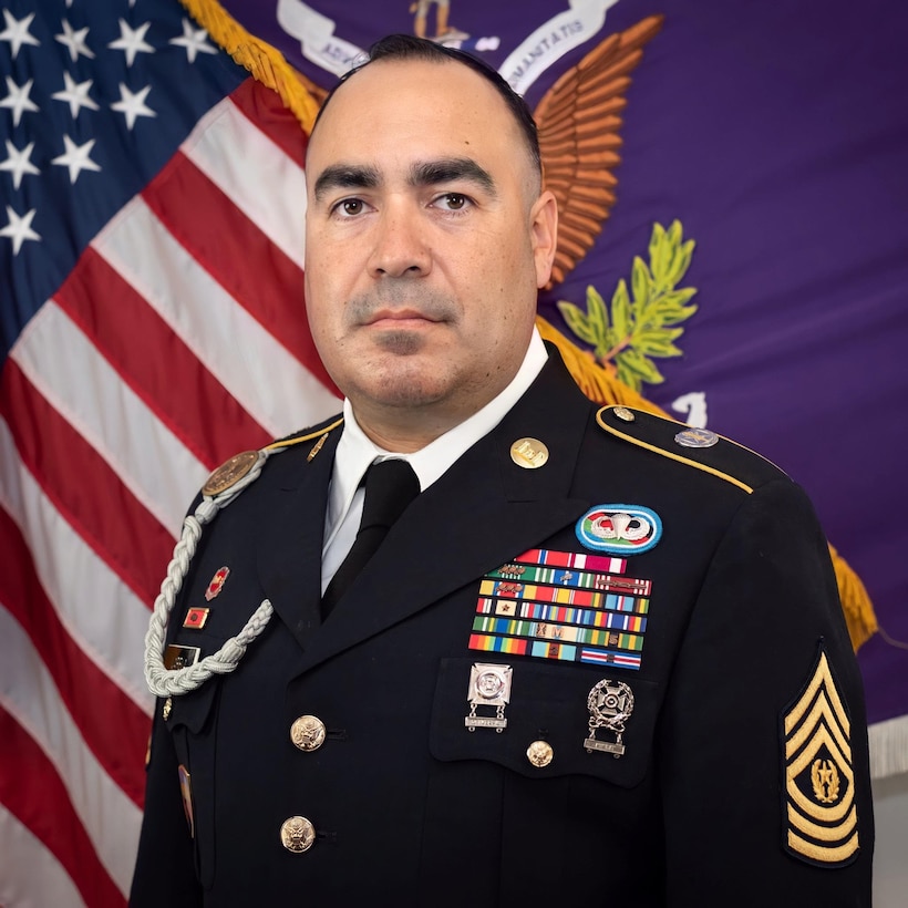 Command Sgt. Maj. Francisco Varela, Command Sgt. Maj. for the 351st Civil Affairs Command in Mountain View, CA., poses in his Army Service uniform in front of the flags of the United States of America and his Civil Affairs Command for his official command portrait.