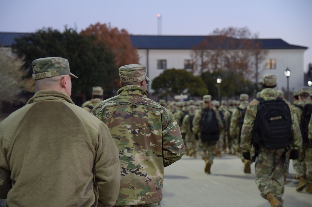 People in military uniform march in formation.