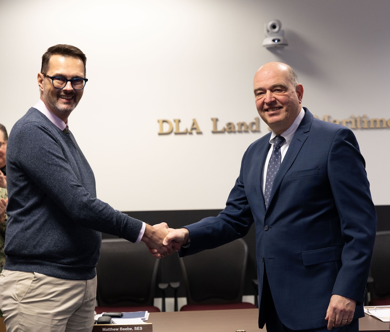 Two men in business dress shake hands.