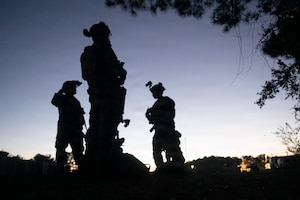 The silhouette of several Airman standing as the sun goes down