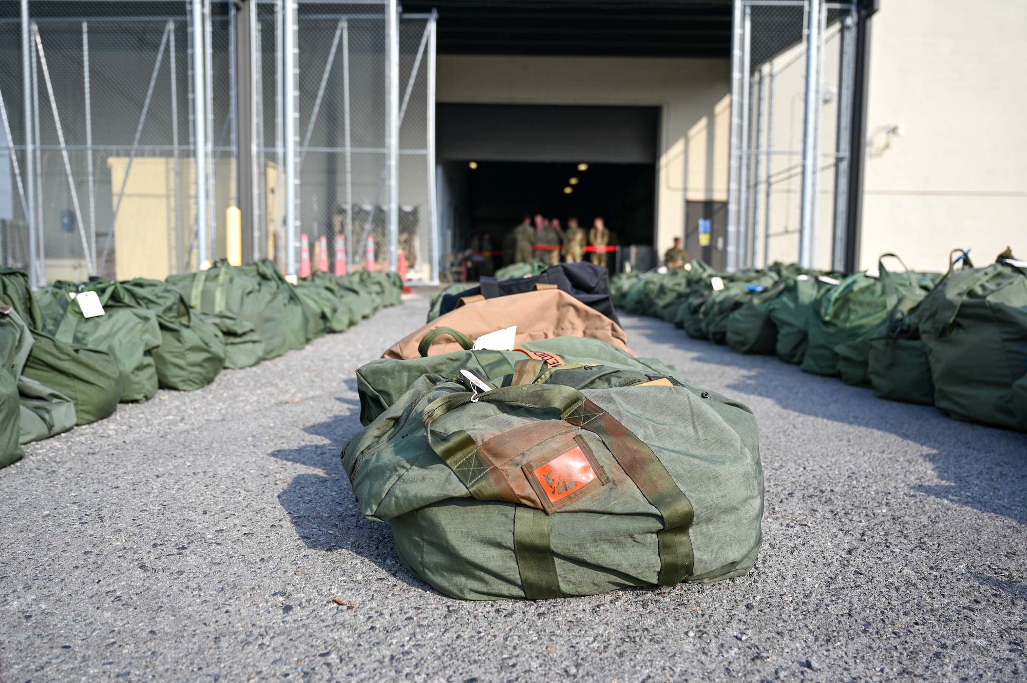 Bags sit on the ground outside of a warehouse building during an exercise.