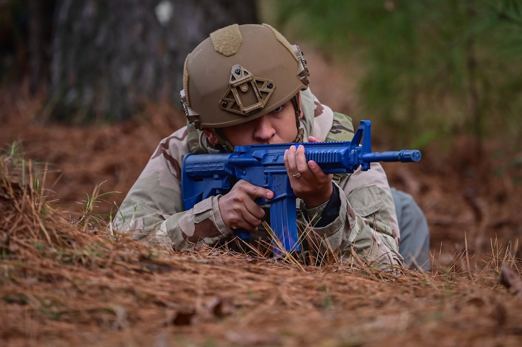 An Airman lies prone with a blue training assault rifle during an exercise.