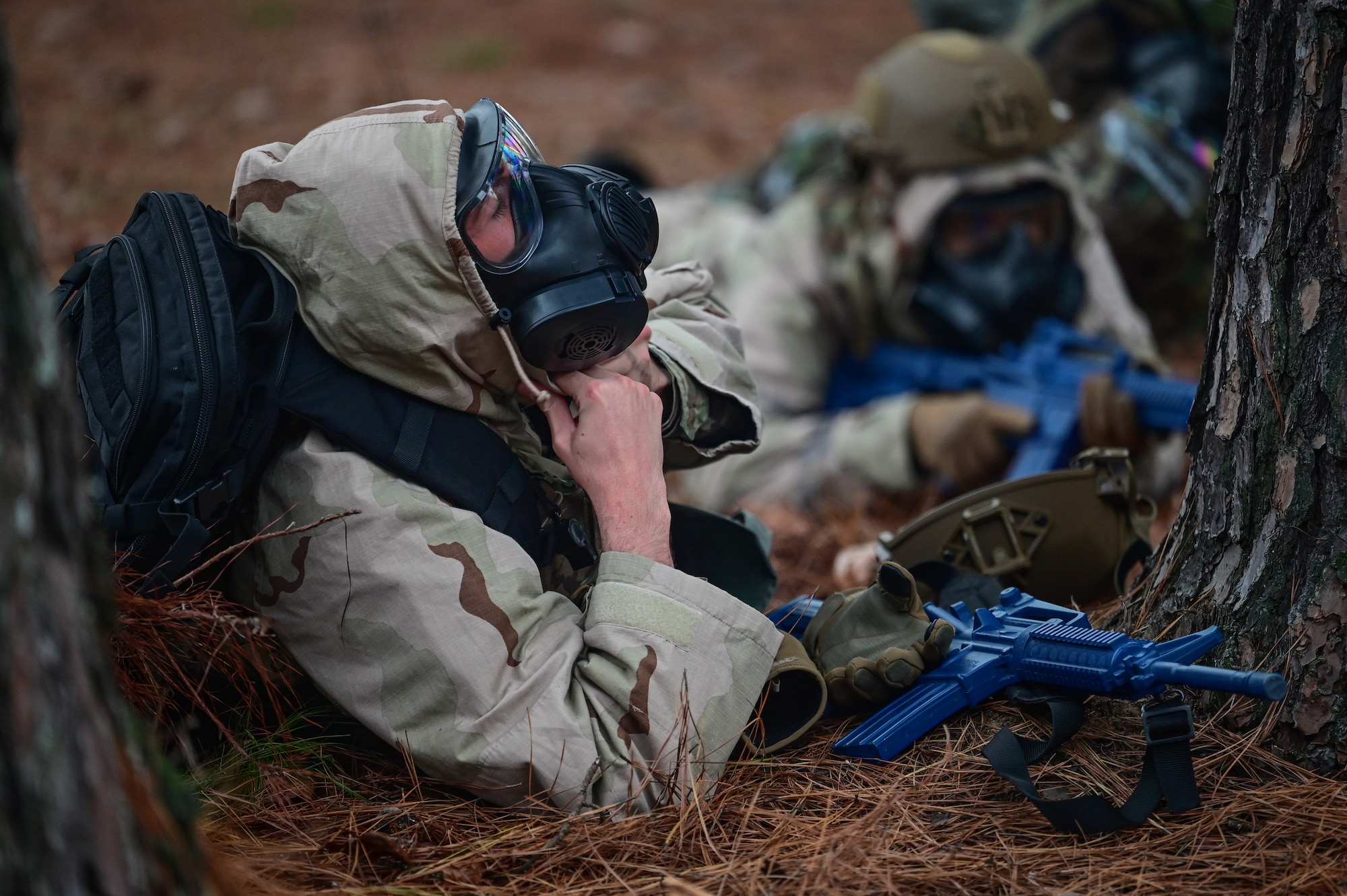 An Airman lies on the ground as he dons a gas mask during an exercise.