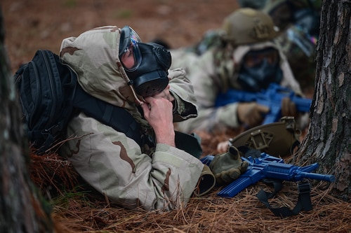 An Airman lies on the ground as he dons a gas mask during an exercise.